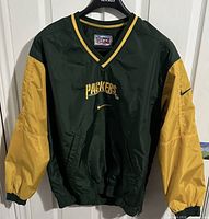 Front view of the Nike Green Bay Packers windbreaker showing green body, yellow sleeves, embroidered Packers logo, and Nike swoosh.
