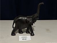 Front and side view of the dark wood African elephant sculpture showing carving details and raised trunk.