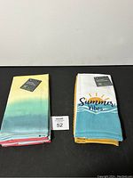 Two packs of kitchen towels displayed side by side, one with a gradient color design and the other with 'Summer Vibes' design.