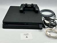 PlayStation 4 console with controller and cables on white background