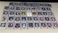 Front view of 78 baseball rookie cards arranged in rows on a flat surface showing multiple individual players in game action from 2022 and 2023 Topps sets.