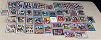 Wide view of the collection showing a large group of vintage football cards spread and stacked on a table, showcasing variety and some cards in sleeves.