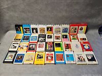 Front view of 36 assorted 8-track tapes arranged in rows showing album cover artwork and colors.