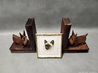 Photo showing the wooden dog and cat bookends with two books and the small framed cat portrait placed in front