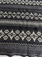 Close-up photo showing detailed black and white geometric diamond patterned design on thick woven wool material.