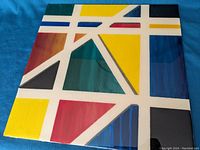 Front view of unsigned encaustic painting with bold geometric shapes in primary colors on canvas board.