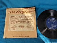 Vinyl record next to its sleeve showing the full design and label on record.