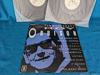Front cover of Roy Orbison Greatest Hits album showing Roy Orbison's face in blue and black with list of featured songs.