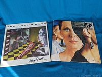 Two vinyl record albums laid out on blue fabric background, showing front covers of Styx and The J. Geils Band albums.
