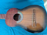 Front angle view of handcrafted wooden Venezuelan guitar with 6 strings, sunburst finish and minor wear.