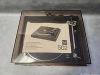 Top‐down view with tinted dust cover closed, manual on platter