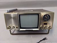 Front view of the vintage Sony micro TV receiver showing small CRT screen, brass/gold finish control area, and tuning dial.