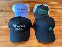 Top view of 4 women's hats on wood table showing front designs and colors.