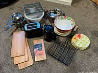 Overview of the kitchen lot showing pots, cedar planks, plastic bowls and plates, toaster, kettle, and grilling rack
