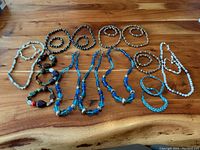 Top view of the entire collection of various beaded bracelets and necklaces arranged on a wooden surface