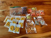 Photo of assorted resin charms including multiple packs of yellow hamburger charms, small packs of miniature amber bottles, and assorted other small resin charms in resealable bags.