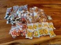 Various resin crafting charms, assorted types and colors, in resealable plastic bags arranged on a wooden surface.