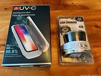 Photo showing new Globe UV-C disinfection box packaging and a cup holder car charger in original packaging on wood surface.
