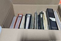 Box filled with multiple albums and folders for stamp storage