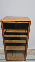 Front view of wooden cabinet with glass doors and shelves inside.