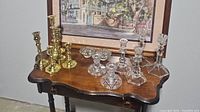 Wide view of candlestick holders on wooden table showing brass and glass pieces arranged together
