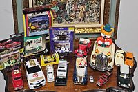Wide shot showing multiple collectible toy cars on a table including NASCAR and vintage styles with a novelty bear figure driving a toy car.