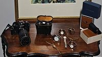 Nikon camera, opera glasses in case and box, seven watches on wooden table