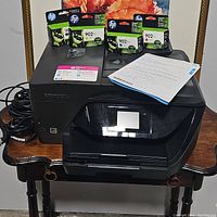 HP OfficeJet Pro 6970 printer with four sealed HP 902XL ink cartridges on top and instruction sheet placed on printer.