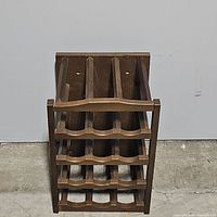 Front view of wooden wine rack showing four shelves with scalloped edges to hold wine bottles horizontally.