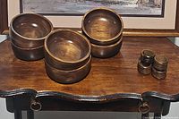 Six wooden bowls and five wooden napkin rings displayed on a wooden table, showing general shape and finish of the items.