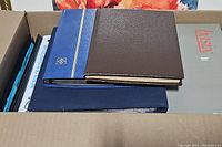 Box of stamp books showing blue and brown hard covers