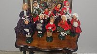 Full view showing all ten caroler figurines arranged on a wooden surface