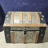 Front view of the large vintage wooden and metal storage chest with metal strap reinforcements and lockable latch.