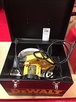 Metal carrying case with DeWalt branding containing the circular saw and its power cord.