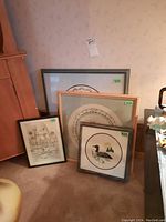 Four framed embroidery arts and prints grouped together, showing different sizes and frame styles.