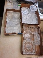 Multiple crystal and glass bowls, plates, and serving dishes in cardboard boxes