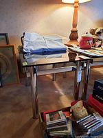 Side perspective showing metal legs and glass top reflecting nearby objects.