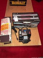 Top view of Wen Wet Sharp grinder, Craftsman belt sander box, and sanding belts on wooden surface