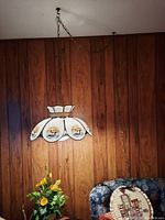 Hanging glass lamp with painted duck motifs in a wood-paneled room