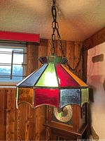 Frontal view of the hanging stained glass lamp showing multicolor glass panels and chain hanging from the ceiling.