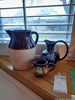 Photo showing all three jugs together on a wooden surface under a window, displaying their size differences and colors.