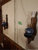 Two oil lamp sconces mounted on a textured wall, showing overall size and installation style.