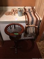 Wooden plant stand, macrame plant hanger with a pot, and owl wall hanging on countertop