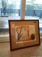 Framed limited edition numbered signed print showing a nude figure reaching into a tree, sitting on the floor in front of a window.