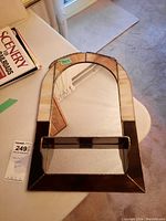 Front view of stained glass mirror showing the brown and cream colored stained glass border and mirror surface with a small shelf at the bottom center.