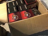 View of partially opened cardboard shipping box containing 20 sealed Ottawa Senators player bobblehead boxes with visible team logos and branding.