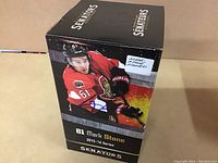 Front view of sealed box displaying Mark Stone image, Senators branding, and signature label