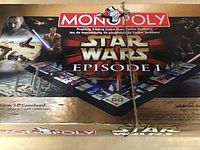 Top down view of the boxed Star Wars Episode I Monopoly board game showing the box art featuring characters and 3D board image.