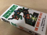 White VHS cover featuring the Teenage Mutant Ninja Turtles and the movie title 'The Secret of the Ooze' with tagline.