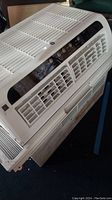 Front and angled view of white GE air conditioner showing vents and control panel.